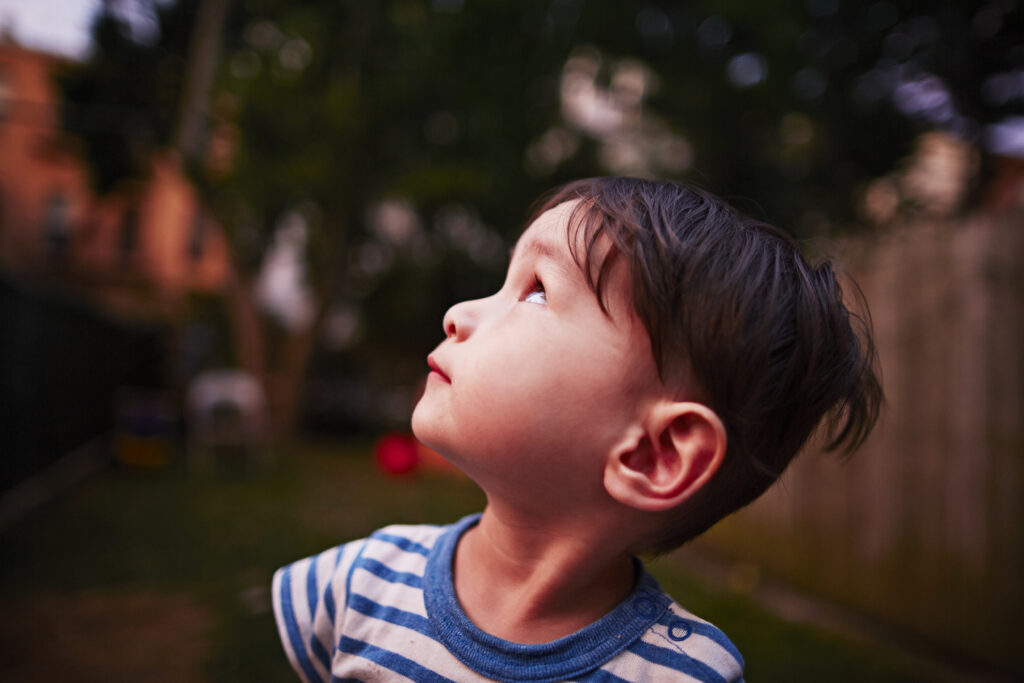 Curious child gazes up at the sky with wonder.