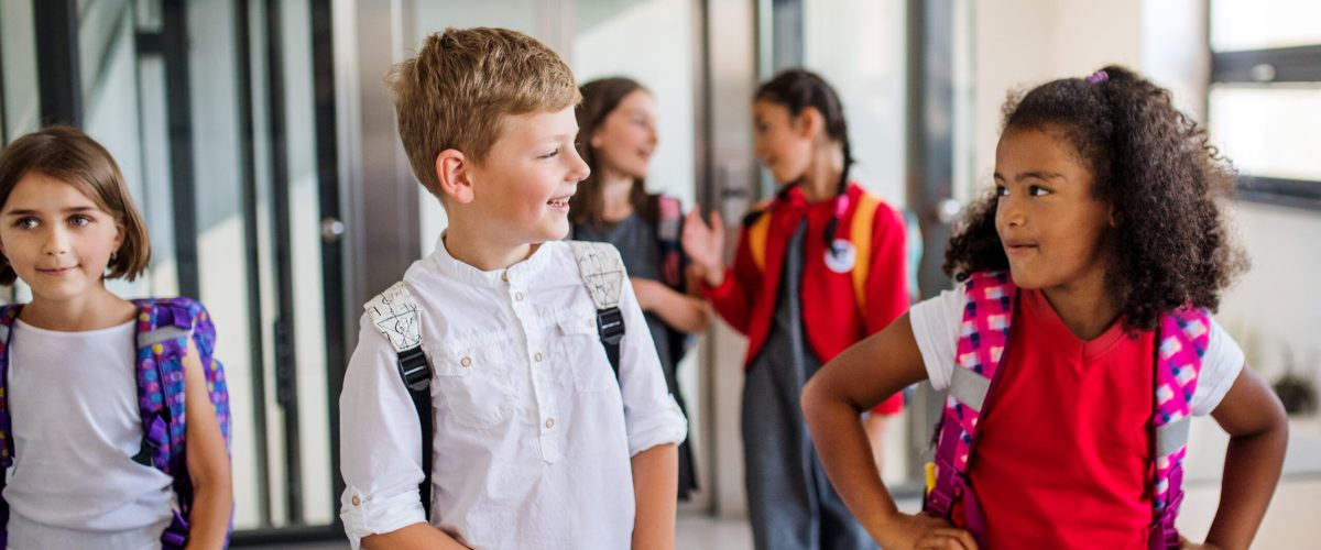Grupa dzieci z torbami idąca korytarzem szkolnym