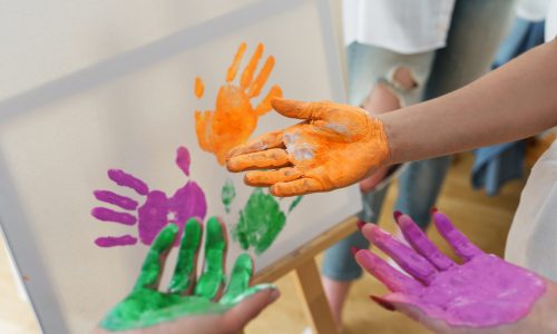 Closeup of female palms in colorful paint creating modern artwork