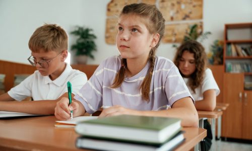 Sitting by the desks. Pupils, kids in the classroom together.