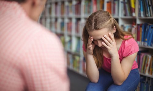 Teacher scolding student in library at school