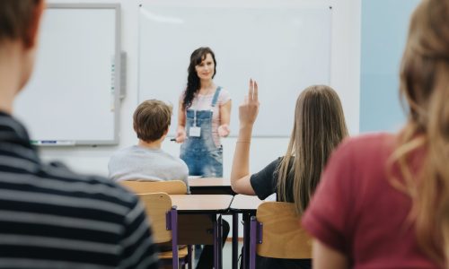 Teacher standing in front of the class room full of teenage students
