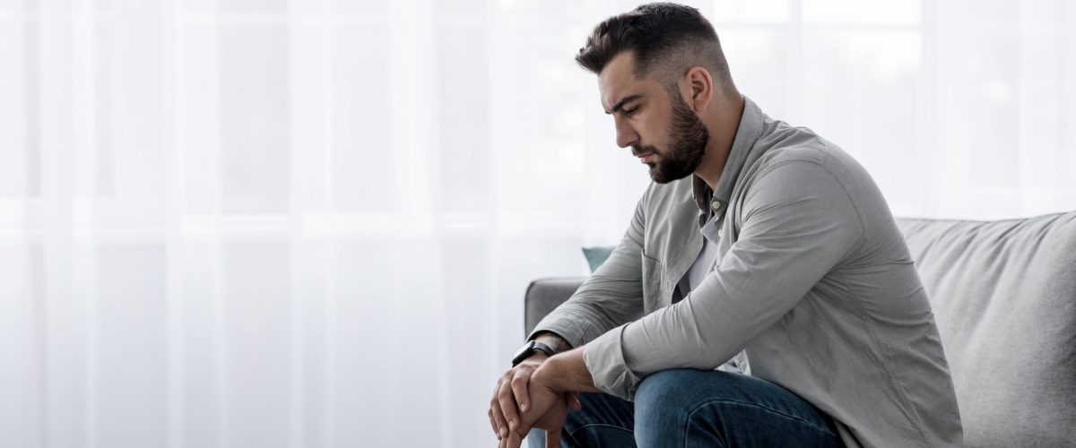 Nieszczęśliwy mężczyzna siedzący w samotności w pokoju.