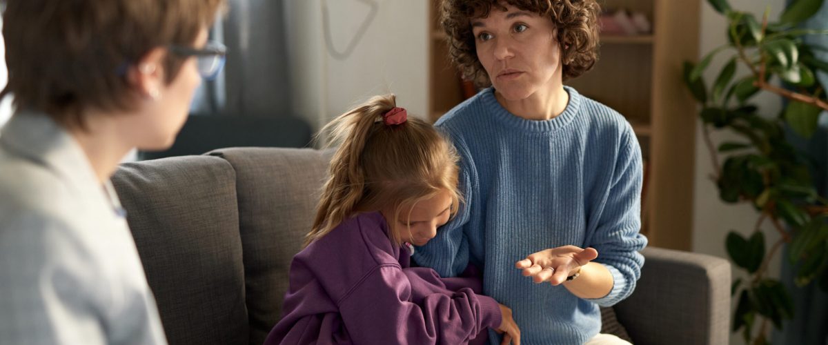 Psycholog rozmawiający z rodzicem i dzieckiem, w domu.