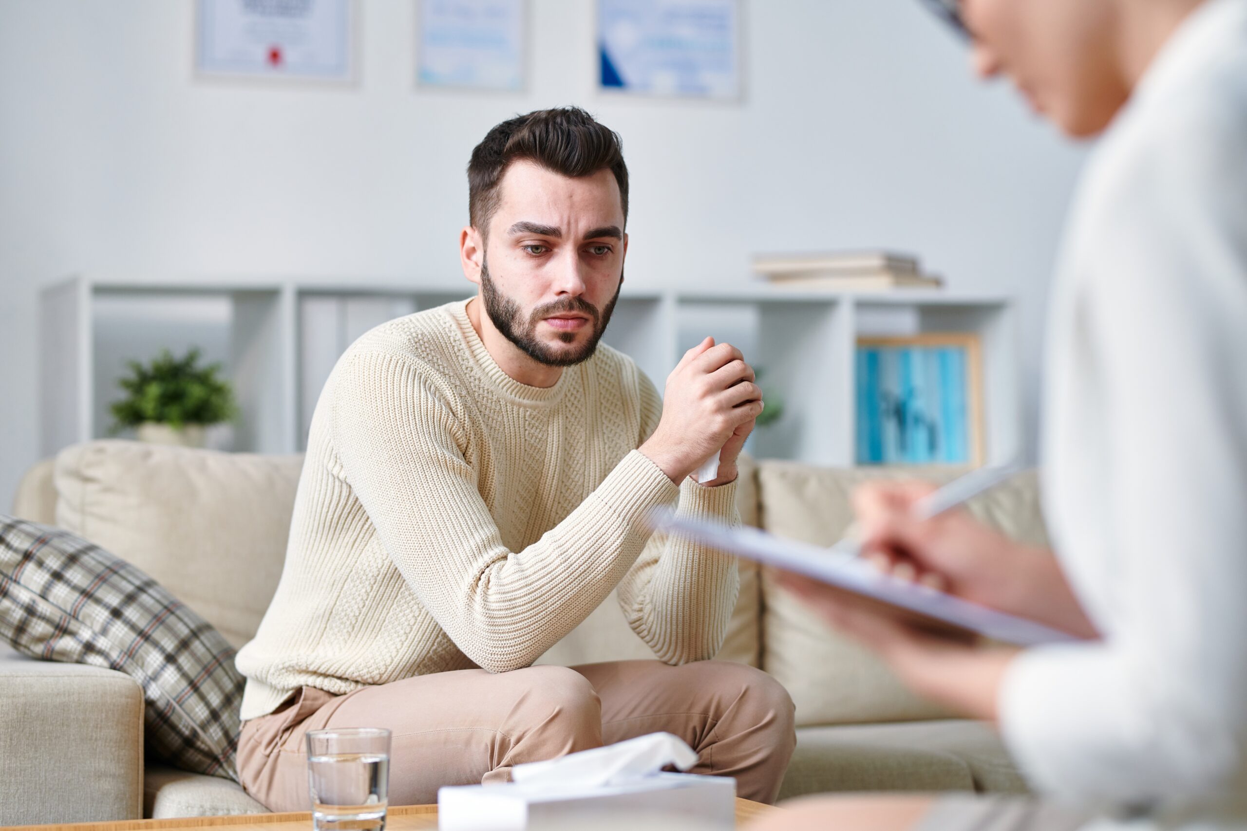 Mężczyzna w białym swetrze podczas konsultacji u lekarza psychiatry.