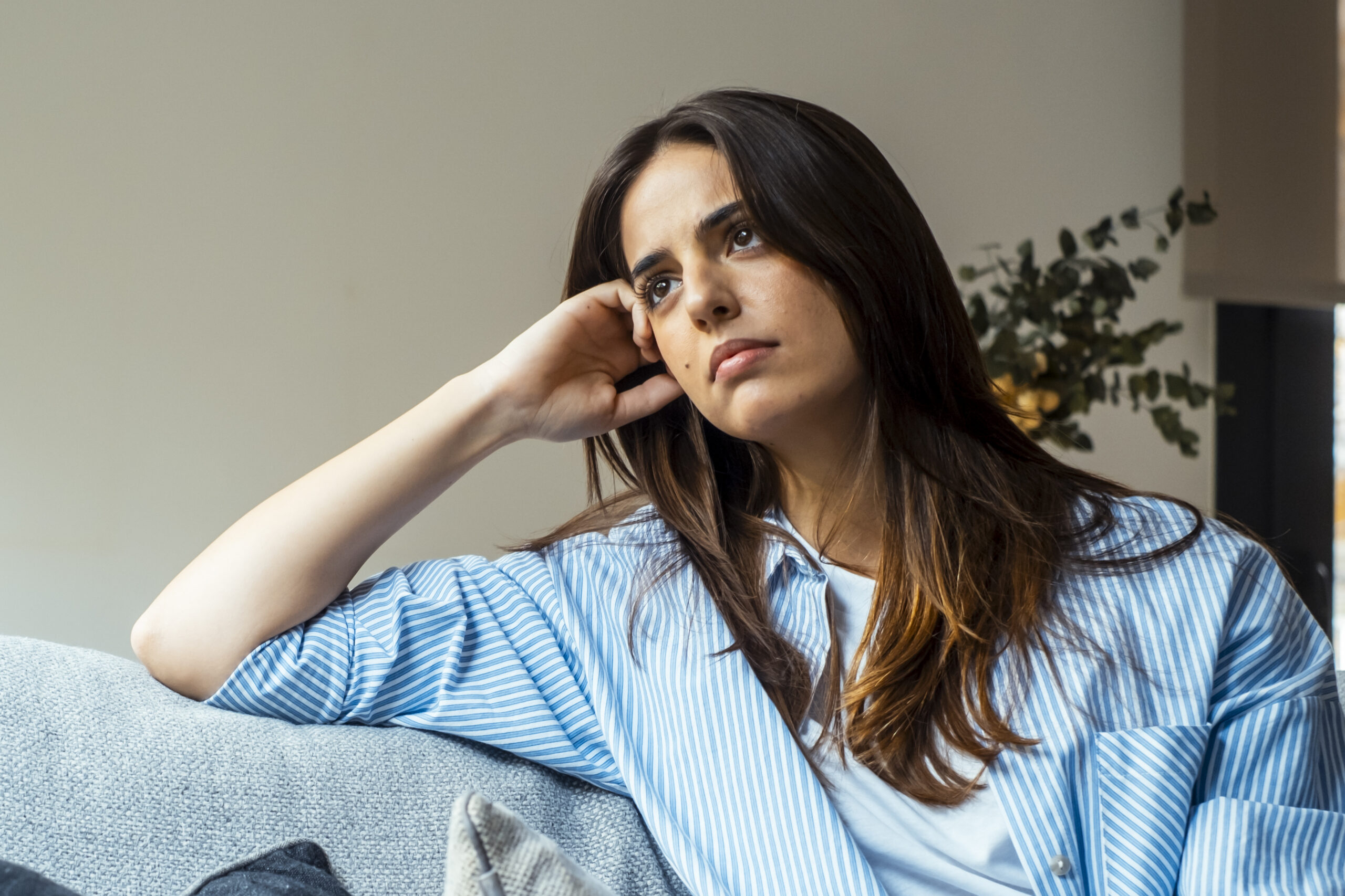 Smutna kobieta w niebieskiej koszulki siedzi w pokoju.