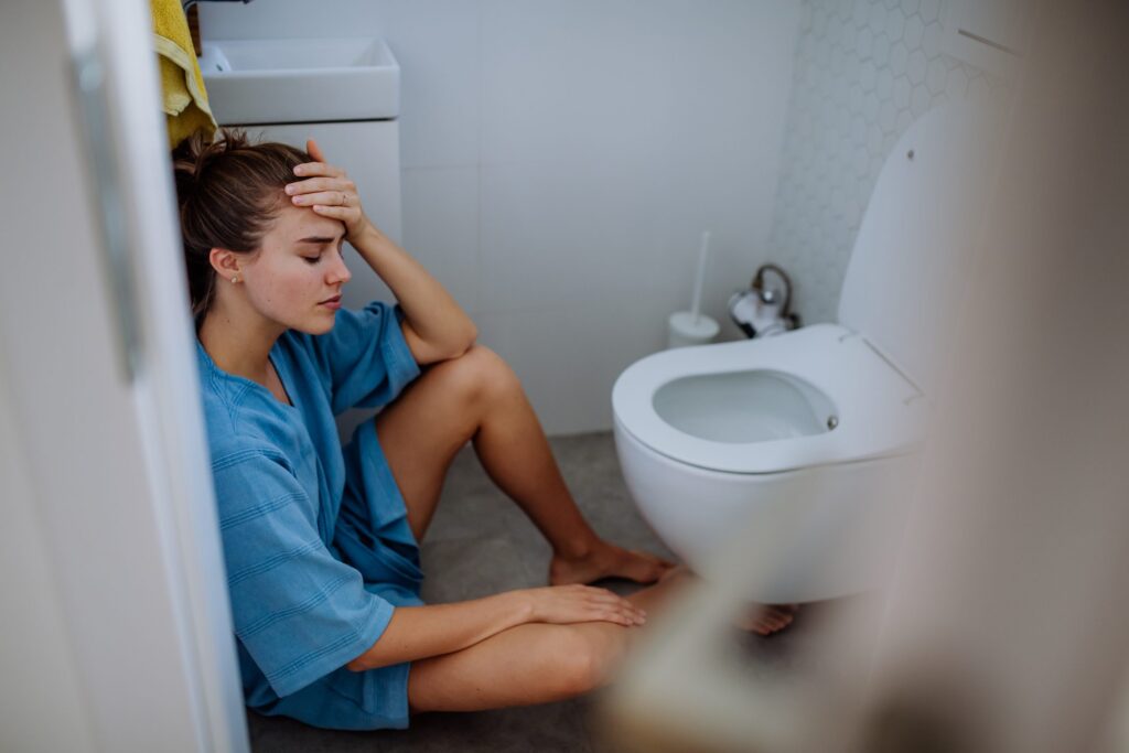 young sick woman sitting on floor near toilet utc scaled