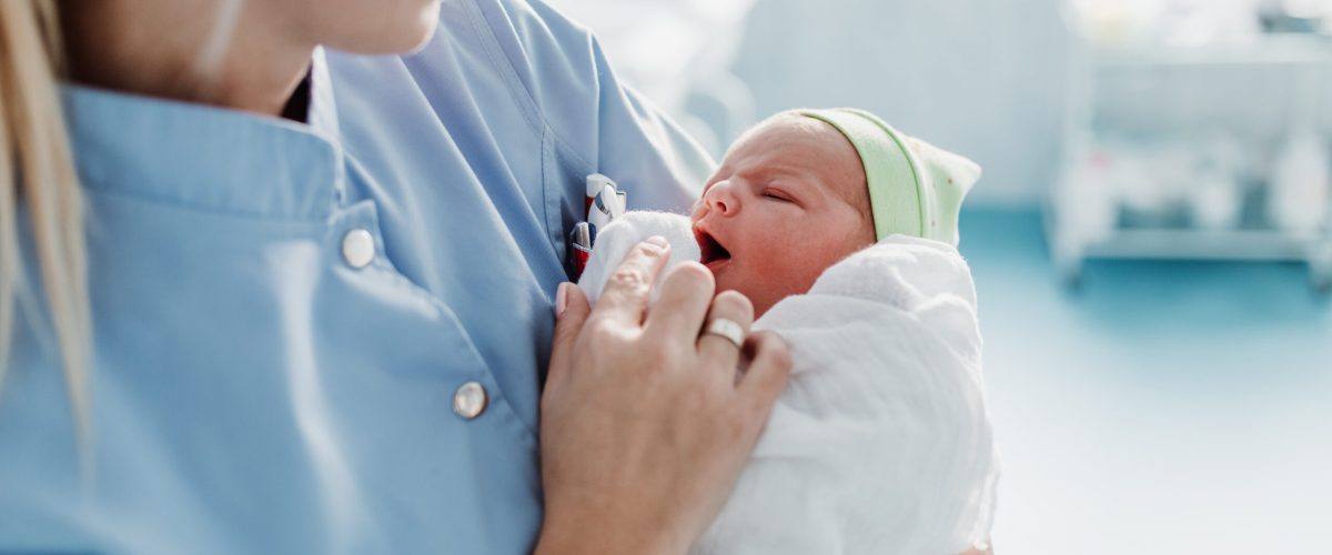 Położna trzyma na rękach noworodka. Zdjęcie ilustracyjne