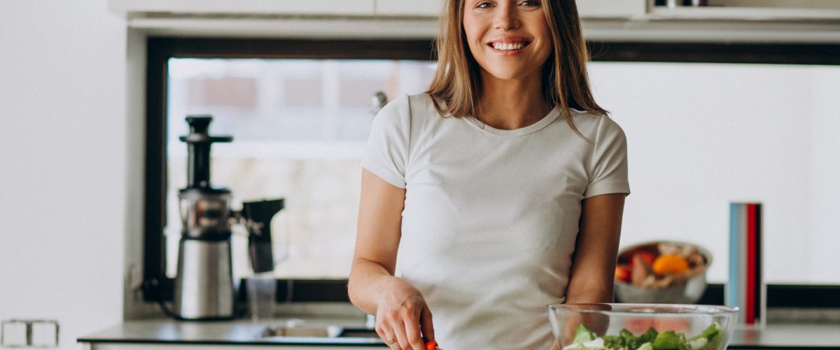 Young woman making salad at the kitchen